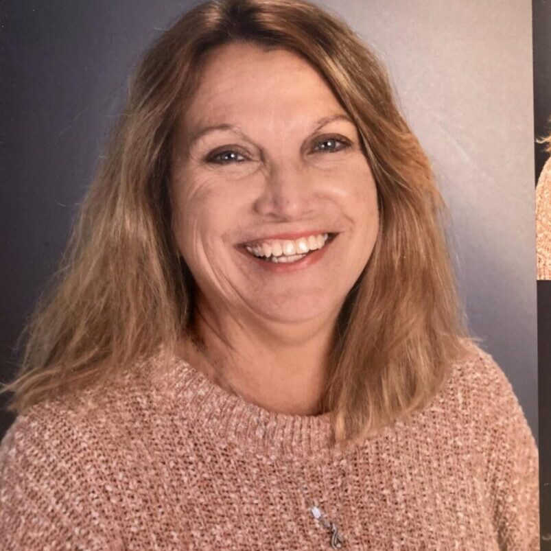 A woman smiling for the camera with her hair down.